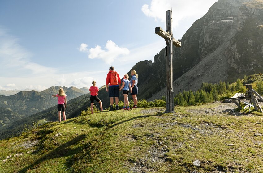 Family at Hahnbalzköpfl summit cross looking out over Gastein valley and surrounding mountains. | © Gasteiner Bergbahnen AG