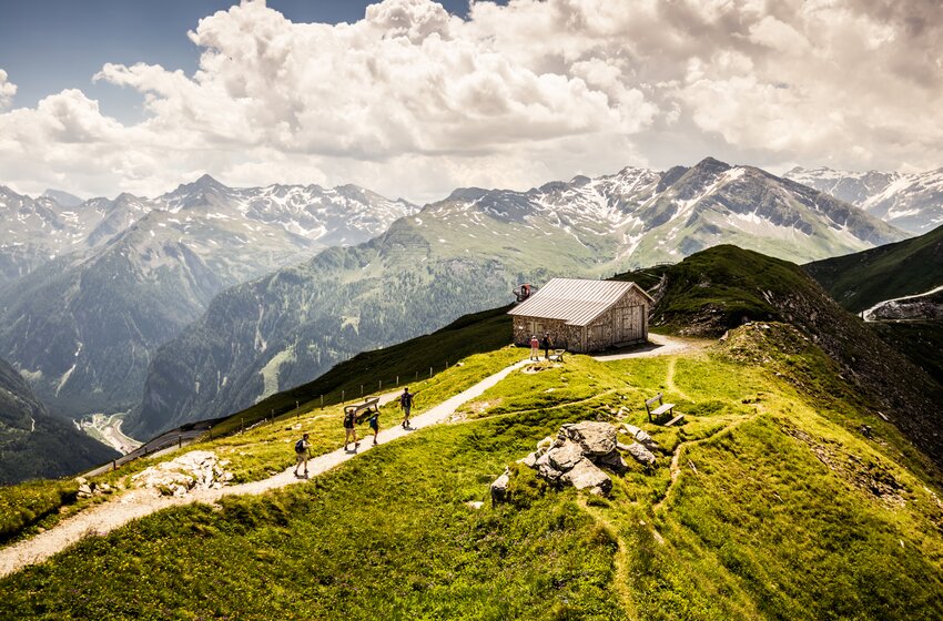 Hikers on alpine trail at Stubnerkogel with hut and panoramic view of the Hohe Tauern mountains. | © Gasteiner Bergbahnen AG
