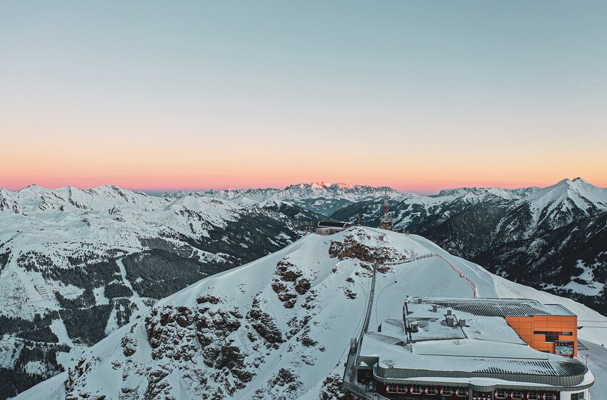 Panorama of snow-covered Stubnerkogel at sunrise with cable car station and alpine mountain view. | © Gasteiner Bergbahnen AG